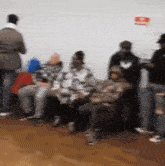 a blurred image of people sitting in a room with a red sign on the wall that says " no smoking "