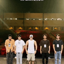 a group of young men are standing in front of an empty auditorium with the words in bangkok written above them