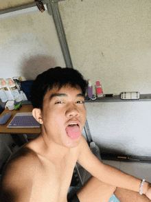 a shirtless man sticking his tongue out in front of a white board