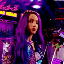 a woman with purple hair is standing in front of a crowd at a wrestling event .