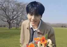 a man holding a bouquet of flowers in a park
