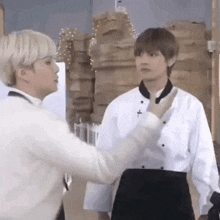 two men in chef 's uniforms are standing next to each other in a kitchen .