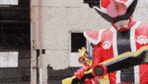 a man in a red and black superhero costume is holding two swords .