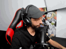 a man wearing headphones and a hat is sitting in front of a microphone ..