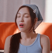a woman wearing a blue tank top and a headband with the letter a on it makes a funny face
