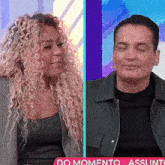 a woman with curly hair and a man with his eyes closed in front of a sign that says do momento assunto