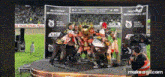 a group of people holding a trophy on a stage .