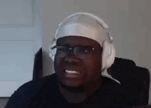 a man wearing headphones and a bandana on his head is sitting in a chair .