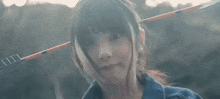 a young girl is holding a bow and arrow in her hair .