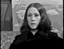 a black and white photo of a woman sitting on a couch .