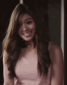a woman in a pink tank top is smiling and looking to the side