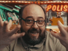 a bald man with glasses and a beard is standing in front of a neon sign that says polis