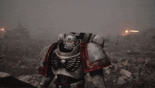 a robot with a skull on his chest is standing on a rock in a field .