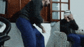 a man wearing a virtual reality headset is sitting in a chair