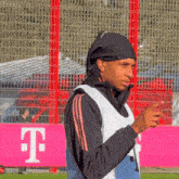 a man wearing a black headband stands in front of a pink t-mobile sign