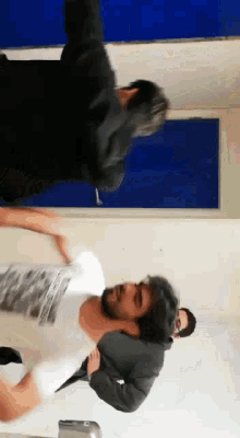 a man in a black jacket is standing next to a man in a white shirt with a picture on it