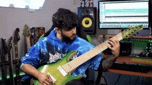 a man in a tie dye hoodie is playing a guitar