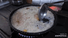 a pan of food is being cooked on a stove and the words made in animotica can be seen in the corner