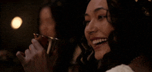 a woman is smiling while holding a cup of wine .