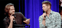 two men are sitting next to each other talking into microphones .