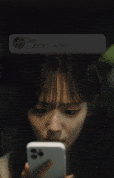 a woman is looking at a phone with a message from kim on the screen