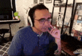 a man wearing headphones and glasses is sitting in front of a microphone in a living room .
