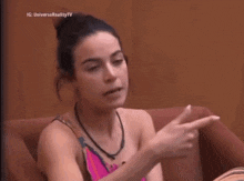 a woman sitting on a couch pointing her finger at something .