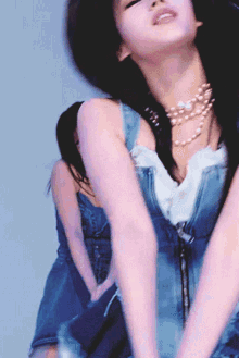 a woman wearing a pearl necklace and a blue dress is dancing