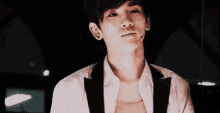 a close up of a young man wearing a white shirt and a black vest .