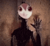 a cartoon character with red eyes is standing in front of a wall and waving .
