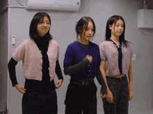 three girls are standing next to each other and one has a fist in her hand