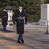 a man in a military uniform is walking in front of a fence