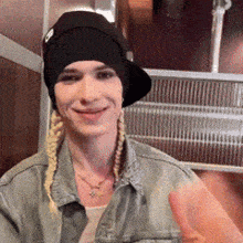 a woman wearing a black hat and a denim jacket is giving a thumbs up