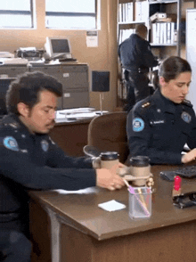 a man and a woman in police uniforms are sitting at a desk in an office