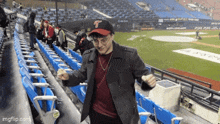 a man wearing a baseball cap with the letter t on it stands in a stadium