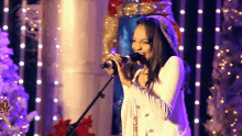 a woman singing into a microphone on a stage
