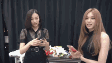 two women are standing next to each other looking at their cell phones