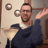 a man wearing glasses holds a martini glass in front of his face