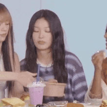 a group of women are sitting at a table eating food and drinking milkshakes .