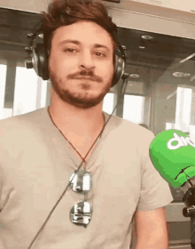 a man wearing headphones and sunglasses is holding a green microphone that says div