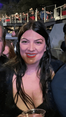 a woman in a black top holds a plastic cup
