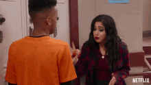 a man in an orange shirt is talking to a woman in a plaid shirt with a netflix logo on the bottom