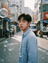 a young man in a blue shirt is surrounded by soap bubbles on a city street