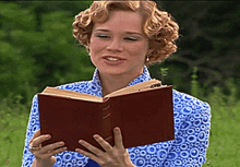 a woman in a blue shirt is reading a book outside