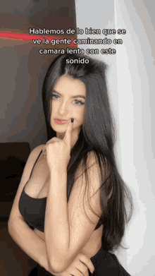 a woman with long black hair is standing in front of a sign that says hablemos de lo bien que se ve la gente caminando en