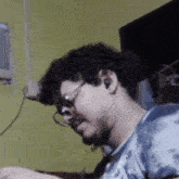 a man wearing glasses and ear buds is sitting in front of a television in a room .