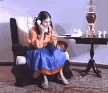 a woman is sitting in a chair and talking on a phone .