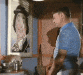 a man in a blue and white striped shirt stands in front of a painting of a clown