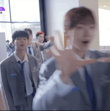 a group of young men in suits and ties are standing in a room