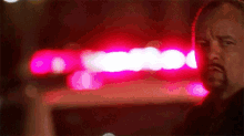 a man with a beard stands in front of a pink light
